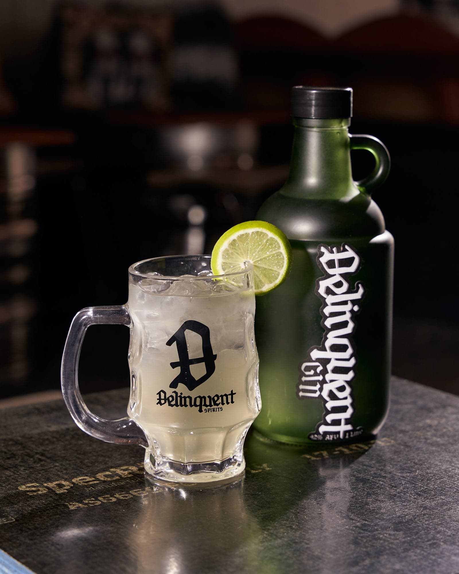 A Delinquent gin and tonic in the branded glass mug beside the one litre growler on a bar top